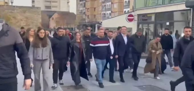 Me shumë persona, Kurti ecën nëpër sheshin e Vushtrrisë me Mehollin dhe Tahirin